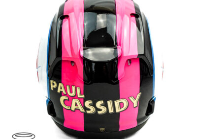 Back of an Arai helmet airbrushed with black and fluorescent pink strips with gold chrome name of rider Paul Cassidy