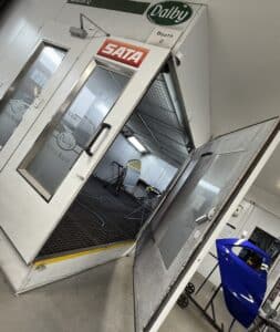 inside a professional dalby spray booth at sandown coachworks featuring a freshly painted blue rear door panel and specialist refinishing facilities used for prestige vehicle paintwork