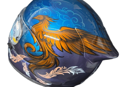 Close up of airbrush painted Arai Quantic motorcycle helmet with gold phoenix rising on blue metallic base